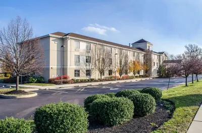 a large building with bushes in front of a street at Sleep Inn & Suites Bensalem in Bensalem
