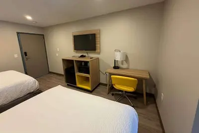 a hotel room with two beds and a desk with a television at Days Inn by Wyndham Moosic in Moosic