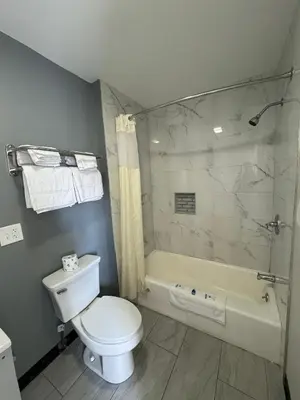a bathroom with a toilet and a shower and a tub at Days Inn by Wyndham Moosic in Moosic