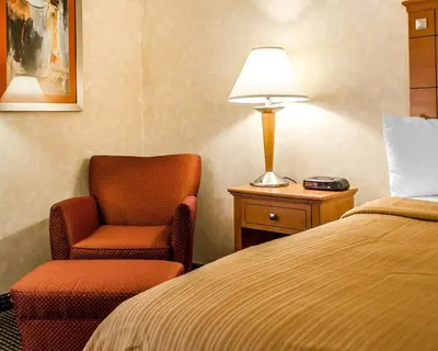a hotel room with a bed and a chair and a lamp at Quality Inn Harrisburg - Hershey Area in Harrisburg