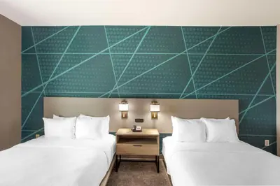 two beds in a hotel room with a green wall at Comfort Suites Bloomsburg in Bloomsburg