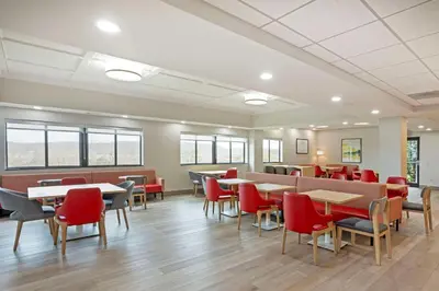 a dining room with tables and red chairs at Comfort Suites Bloomsburg in Bloomsburg