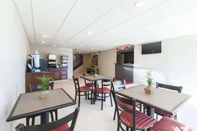 a dining room with tables and chairs and a kitchen at Econo Lodge Harrisburg - Southwest of Hershey Area in Harrisburg