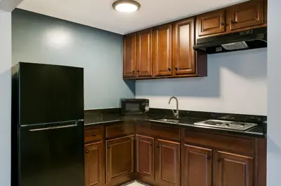 a kitchen with wooden cabinets and a black refrigerator at HomeTowne Studios by Red Roof Denver, PA in Denver