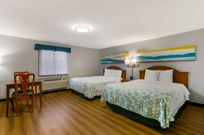 a hotel room with two beds and a table and chair at HomeTowne Studios by Red Roof Denver, PA in Denver