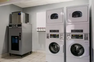 a laundry room with three washing machines and a microwave at HomeTowne Studios by Red Roof Denver, PA in Denver