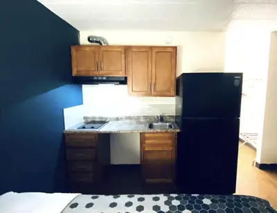 a kitchen with wooden cabinets and a black refrigerator at Travelodge by Wyndham Shamokin Dam/Selinsgrove in Shamokin Dam