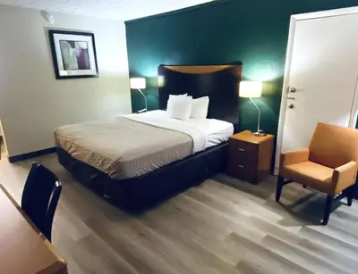 a hotel room with a bed and a chair at Travelodge by Wyndham Shamokin Dam/Selinsgrove in Shamokin Dam