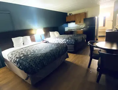 a hotel room with two beds and a table at Travelodge by Wyndham Shamokin Dam/Selinsgrove in Shamokin Dam