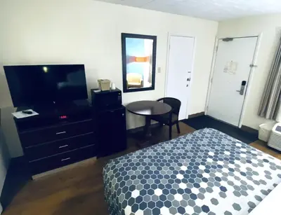 a bedroom with a bed and a table and a television at Travelodge by Wyndham Shamokin Dam/Selinsgrove in Shamokin Dam