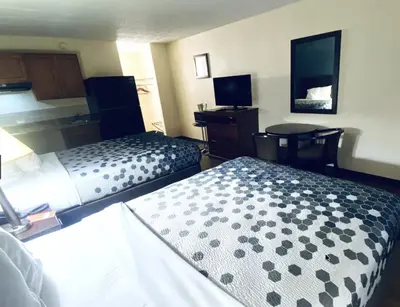 a hotel room with two beds and a desk at Travelodge by Wyndham Shamokin Dam/Selinsgrove in Shamokin Dam