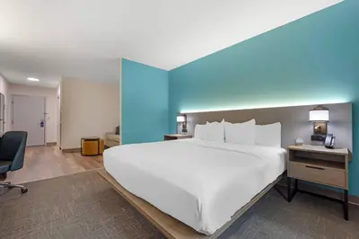a large white bed in a room with a blue wall at Comfort Suites Lewisburg near University in Lewisburg