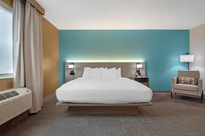 a bedroom with a large white bed and a chair at Comfort Suites Lewisburg near University in Lewisburg
