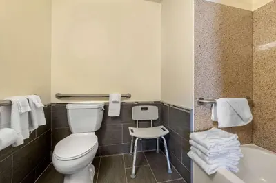 a bathroom with a toilet and a tub and a stool at MainStay Suites Grantville - Hershey North in Grantville