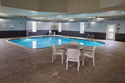 a pool with a table and chairs in front of it at MainStay Suites Grantville - Hershey North in Grantville