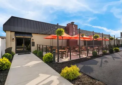 a patio with tables and umbrellas in front of a building at Red Roof Inn Reading in Reading