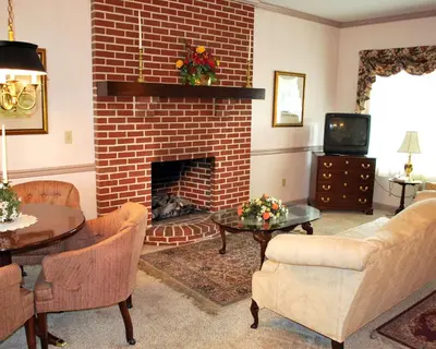 a living room with a brick fireplace and a tv at Rodeway Inn & Suites Myerstown - Lebanon in Myerstown