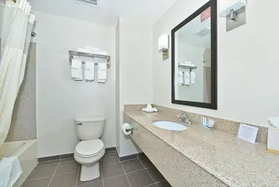a bathroom with a toilet and a sink and a mirror at Sleep Inn & Suites Harrisburg - Hershey North in Harrisburg