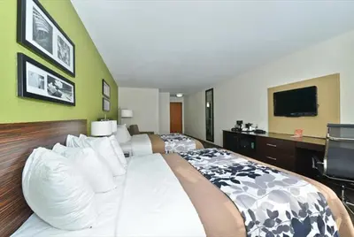 a hotel room with a large bed and a flat screen tv at Sleep Inn & Suites Harrisburg - Hershey North in Harrisburg