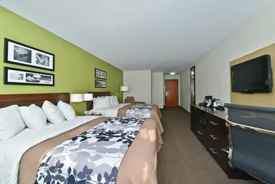 a hotel room with two beds and a flat screen tv at Sleep Inn & Suites Harrisburg - Hershey North in Harrisburg