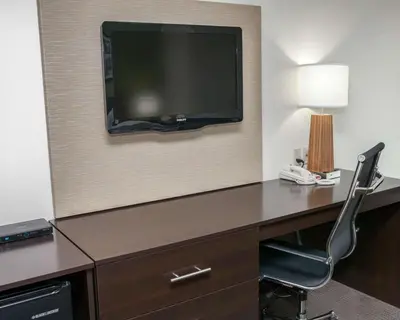 a room with a desk with a television and a chair at Sleep Inn & Suites Harrisburg - Hershey North in Harrisburg