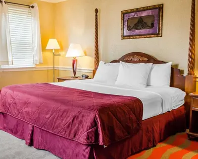 a bedroom with a large bed with a red blanket at Clarion Inn Strasburg - Lancaster in Strasburg