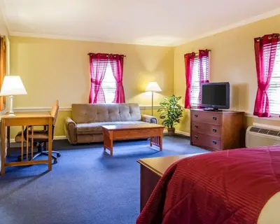 a hotel room with a bed and a couch and a tv at Clarion Inn Strasburg - Lancaster in Strasburg