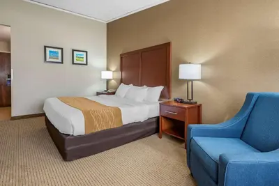 a hotel room with a bed and a blue chair at Comfort Inn Lancaster County North in Denver