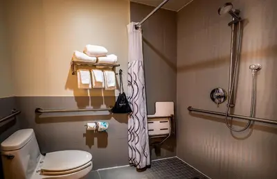 a bathroom with a shower and a toilet and towels at La Quinta by Wyndham Time Square South in New York