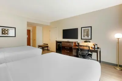 a hotel room with two beds and a desk and a tv at The Prussia Hotel in King of Prussia