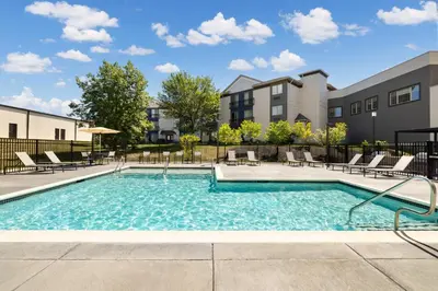a swimming pool with chairs and a building at The Prussia Hotel in King of Prussia
