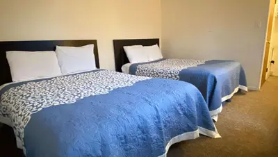 two beds in a room with blue and white sheets at Country Place Inn and Suites White Haven in White Haven