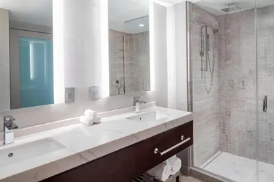 a white bathroom with a sink and a shower at Envue, Autograph Collection in Weehawken
