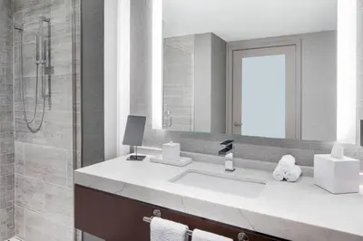 a bathroom with a sink and a shower and a mirror at Envue, Autograph Collection in Weehawken