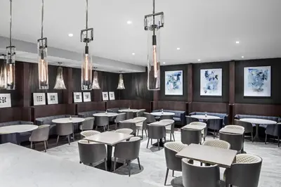 a dining room with tables and chairs and chandeliers at Envue, Autograph Collection in Weehawken