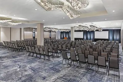 a conference room with a rows of chairs and chandeliers at Envue, Autograph Collection in Weehawken