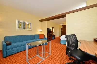 a hotel room with a blue couch and a bed at Fairfield Inn & Suites by Marriott Elmira Corning in Horseheads
