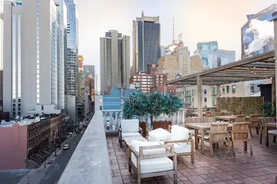 a balcony with white chairs and tables and a city skyline at Hotel Scherman in New York