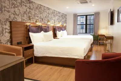 a hotel room with two beds and a table and chairs at Hotel Scherman in New York