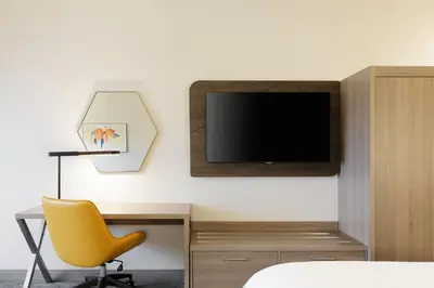 a bedroom with a desk and a tv and a yellow chair at Holiday Inn Express and Suites Limerick - Pottstown by IHG in Limerick