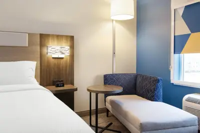 a hotel room with a bed and a chair at Holiday Inn Express and Suites Limerick - Pottstown by IHG in Limerick