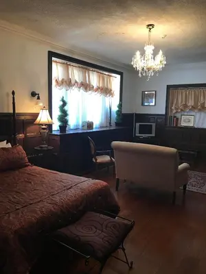 a bedroom with a bed and a chair and a chandelier at The Castle at Skylands Manor in Ringwood