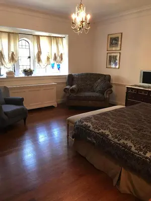 a bedroom with a bed and a couch and a chandelier at The Castle at Skylands Manor in Ringwood