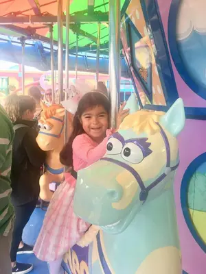 a little girl is standing on a carousel at 106 Village at Camelback in Tannersville