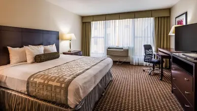 a hotel room with a bed and a desk and a computer at Best Western Plus Philadelphia Airport South - at Widener University in Chester