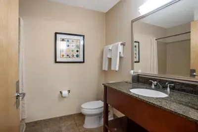 a bathroom with a sink and a toilet and a mirror at Best Western Plus Philadelphia Airport South - at Widener University in Chester