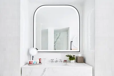 a white bathroom with a mirror and a sink at The Luxury Collection Hotel Manhattan Midtown in New York