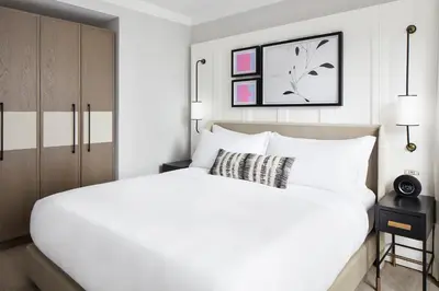 a white bedroom with a large white bed and cabinets at The Luxury Collection Hotel Manhattan Midtown in New York