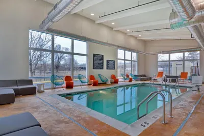 a swimming pool with chairs and a couch and a table at Aloft Secaucus Meadowlands in Secaucus