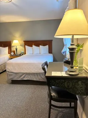 a hotel room with a bed and a desk with a lamp at SHERWOOD MOTEL in Wellsboro